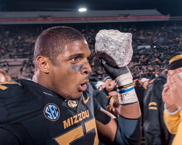 Fans flock senior defensive end Michael Sam as he carries his souvenir (a rock from the rock 'M' at Memorial Stadium) after the win vs Texas A&M. 30 November 2013. Photo by Mark Schierbecker (Marcus Qwertyus). CC BY-SA 3.0 via Wikimedia Commons