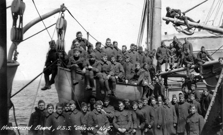 Homeward bound troops pose on the ship's deck and in a lifeboat, 1919. The original image was printed on postal card ("AZO") stock. Public Domain