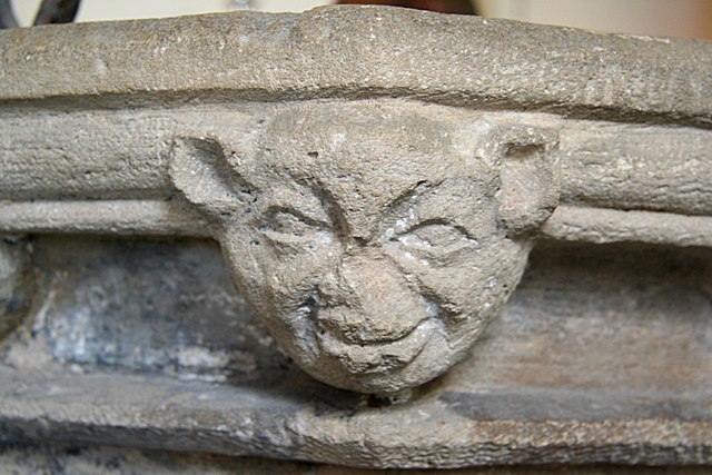 An authentic cluck-ma-doodle. (An impish face carved on St. Mary's 14th century font, Knaith. Photo by Richard Croft. CC BY-SA 2.0 via Wikimedia Commons)