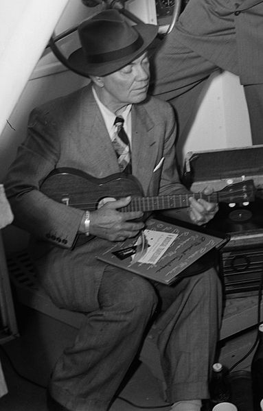 Cliff Edwards playing ukulele with phonograph, 1947. Photography from the William P. Gottlieb Collection. Public domain via Wikimedia Commons.