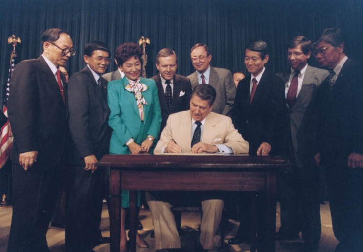 President Ronald Reagan signing the Japanese reparations bill.
