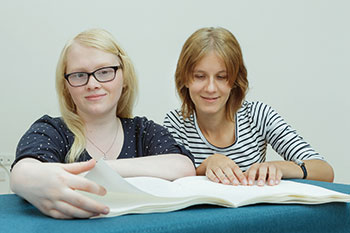 Photo of two women reading Braille literature