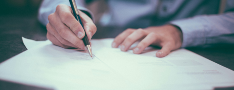 A close-up of a pair of hands writing on paper.