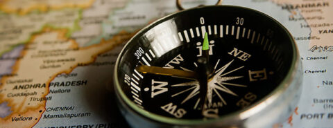 Compass pointing to north on top of a paper map.