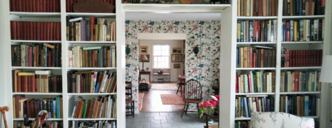 Room full of white bookshelves full of books surrounding a doorway